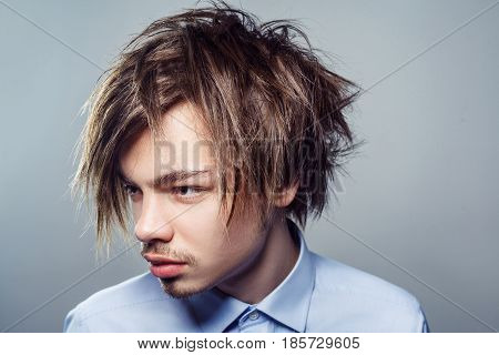 Portrait of young man with fringe messy hairstyle. studio shot.