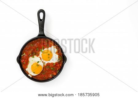 Mexican breakfast: Huevos rancheros in iron frying pan isolated on white background