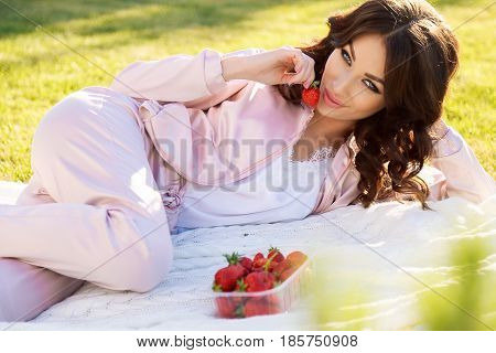 Beautiful Girl With Dark Hair Relaxing At Summer Picknic, Eating Strawberries