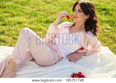 Beautiful Girl With Dark Hair Relaxing At Summer Picknic, Eating Strawberries
