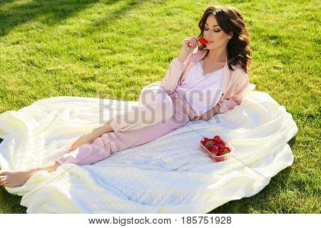 Beautiful Girl With Dark Hair Relaxing At Summer Picknic, Eating Strawberries