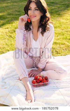 Beautiful Girl With Dark Hair Relaxing At Summer Picknic, Eating Strawberries