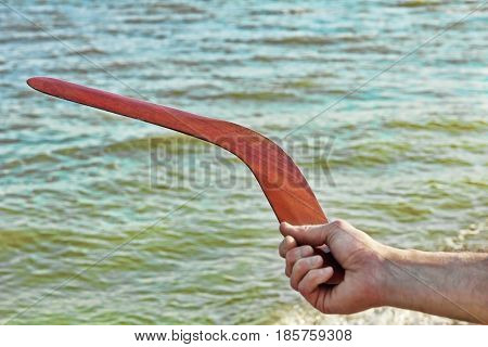 Boomerang in men arm taken closeup against of the turquoise sea.