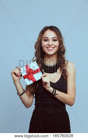 Young woman holding a gift box isolated on gtay background