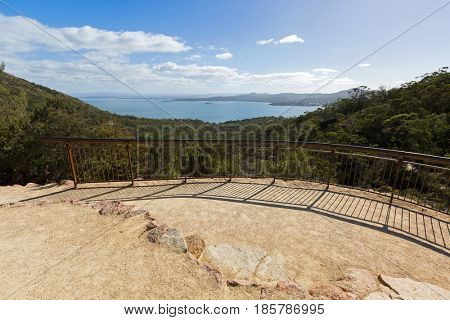 Metal fence embedded in cliff at viewing platform overlooking Coles Bay, on Wineglass Bay track, Tasmania's famous east coast in Freycinet National Park, Tasmania island, Australia