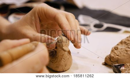 Female sculptor is modeling clay figurine or creating pottery ceramics statuette. Art and handicraft modelling creation.