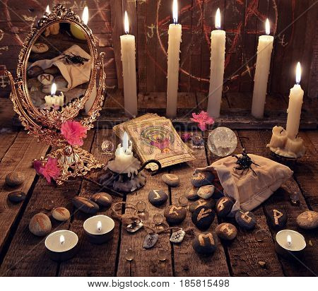 Mystic ritual with burning candles, magic mirror, flowers and the tarot cards. Halloween background, black magic rite or spell, occult and esoteric objects on witch table