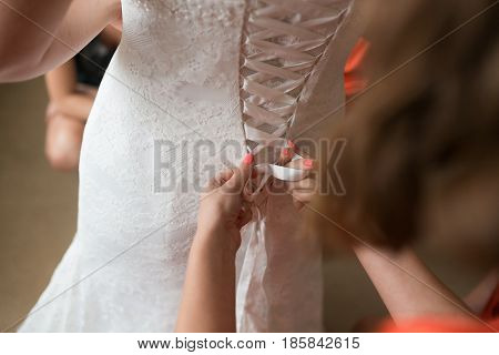 Bridesmaid dresses bride for the wedding day. Bridesmaid helps with a white dress before the ceremony. Luxury bridal dress close up. Best wed morning. concept.