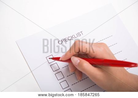 Close-up of hand marking on checklist with red pen
