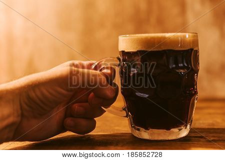 Man drinking dark beer in british dimpled glass pint mug on bar table