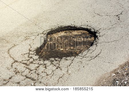 Asphalt road hole damage close up of damaged driveway