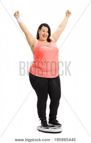 Full length portrait of an overweight woman standing on a weight scale and gesturing happiness isolated on white background