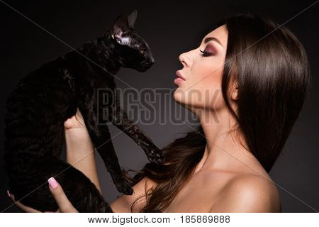 portrait of the beautiful young woman with cat on the black background
