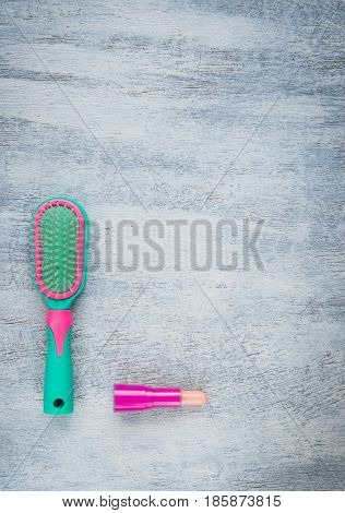 Green and pink hairbrush lipstick on a light wooden background
