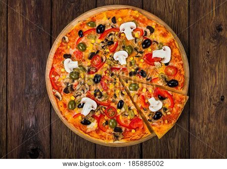 Italian pizza top view on wood with ham, tomatoes and black olives - thin pastry crust