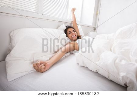 Smiling Young Woman Stretching Her Hand While Waking On The Bed