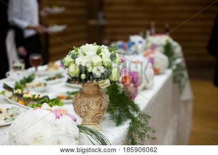 White bouquet stands in the earthware vase