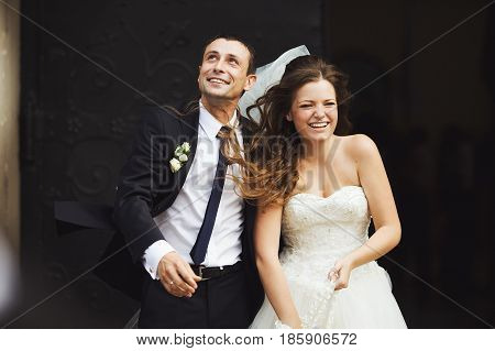 Wind Blows Newlyweds Clothes While They Stand In The Entrance To The Cathderal