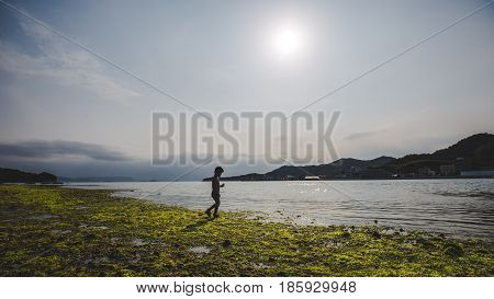 Silhouette of a child on a stony beach, walking by the water, Shodoshima