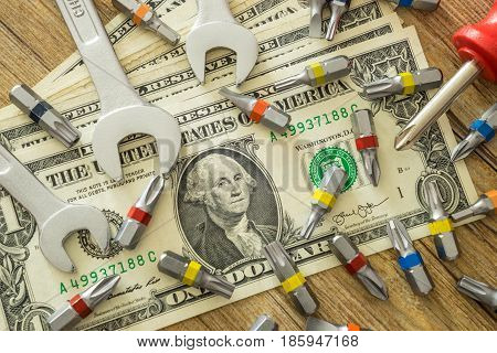 Maintenance tools with dollars money on wooden table