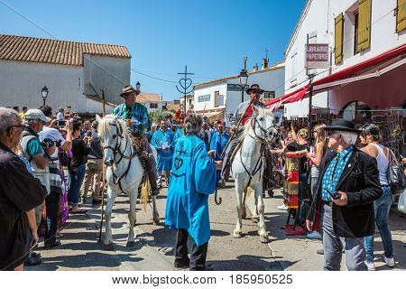 Saintes-Maries-de-la-Mer, Provence, France - May 25, 2015. Religious feast in honor of the Holy Maries. Guards on white horses and participants in a procession. The concept of ethnographic tourism