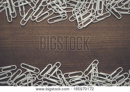 many white paperclips. paperclips on the brown table. paperclips on wooden background. paperclips background with copy space