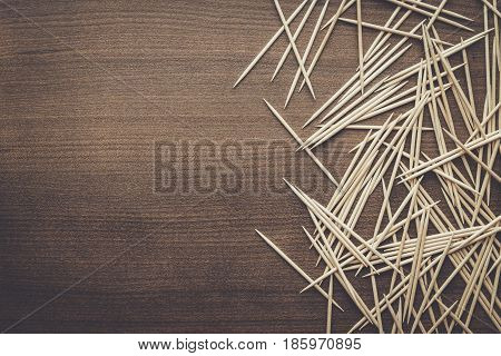 many wooden toothpicks. toothpicks on the brown table. toothpicks on wooden background. toothpicks background with copy space