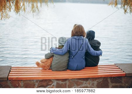 mother of two boys sitting on a bench near the river