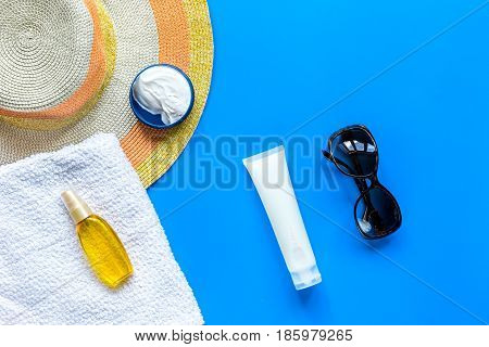 Sun protection composition with glasses and body cream on blue desk background top view mockup