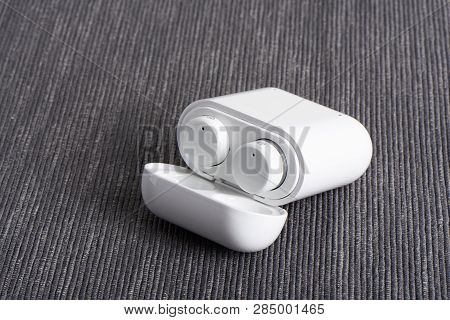 Wireless Cordless Bluetooth Earbuds With Chargeable Case On A Fabric Background