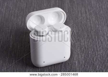 Wireless Cordless Bluetooth Earbuds With Chargeable Case On A Fabric Background