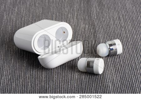 Wireless Cordless Bluetooth Earbuds With Chargeable Case On A Fabric Background