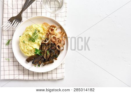Sliced Grilled Beef Liver With Mashed Potatoes And Fried Onion Rings On White Plate Over Stone Backg