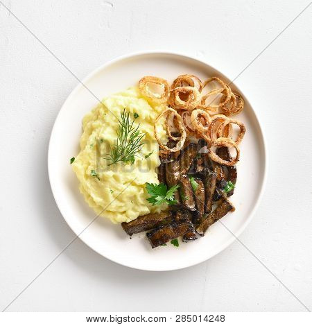 Close Up Of Mashed Potatoes With Roasted Beef Liver And Fried Onion Rings On White Plate Over Stone 