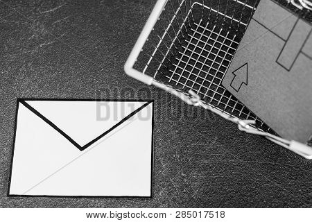 Shopping Cart With Cardboard Parcel And Email Envelope On Concrete Desk, Concept Of Shipping And Tra