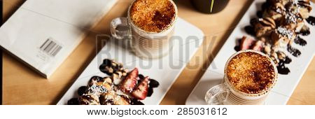 Banner Size Image Of Two Cups Of Hot Latte With Baked Caramel Crust And Sweet Roll With Banana And S