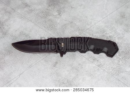 Black Folding Knife On A Marble Slab