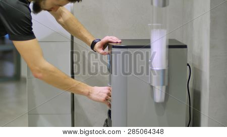 Pouring Of Water Into A Glass From The Watercooler