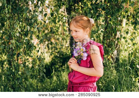Summer Portrait Of Cute Little Girl Holding Small Bouquet Of Wild Flowers