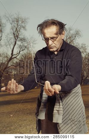 Man In Ugly Style Dress Practicing In Dowsing With Rods