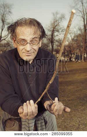 Man In Ugly Style Dress Practicing In Dowsing With Rods