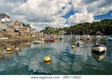 Fowey, Uk - March 23, 2010: Town Quay, Green Trees At River Harbor With Boats On Water On Cloudy Blu