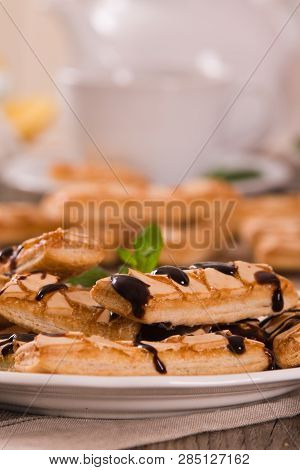 Puff Pastry Cookies With Chocolate Icing On White Dish.