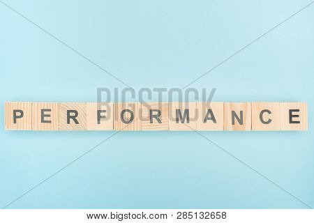 Top View Of Performans Lettering Made Of Wooden Cubes On Blue Background