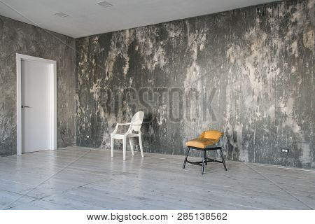 Modern Light Loft-style Room With Designer Chairs And Lighting. Gray Walls With The Texture Of The C