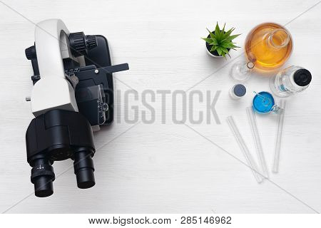 Laboratory Table With A Microscope And A Chemical Reagent Liquids Above. Chemistry Or Pharmacy Backg
