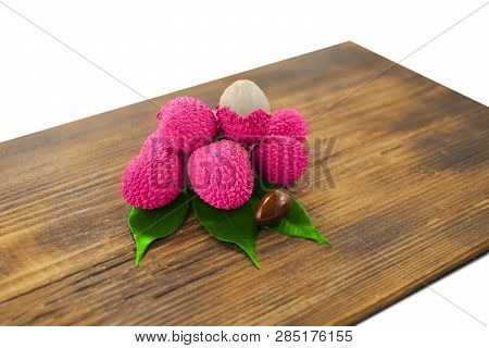 Fresh Lychee And Peeled Showing The Red Skin And White Flesh With Green Leaf On A Wooden Background.