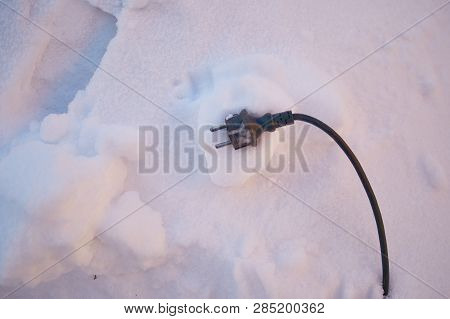 Black Electric Wire From The Device Lies On The Snow