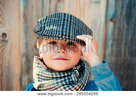 Cute Stylish Boy. Boy In A Cap. A Child In A Village On A Wooden Background. Spring Children Fashion