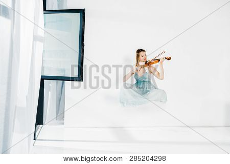 Floating Girl In Blue Dess Playing Violin On White Background